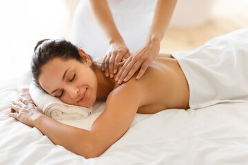 Caucasian lady with eyes closed experiences therapeutic back massage indoors