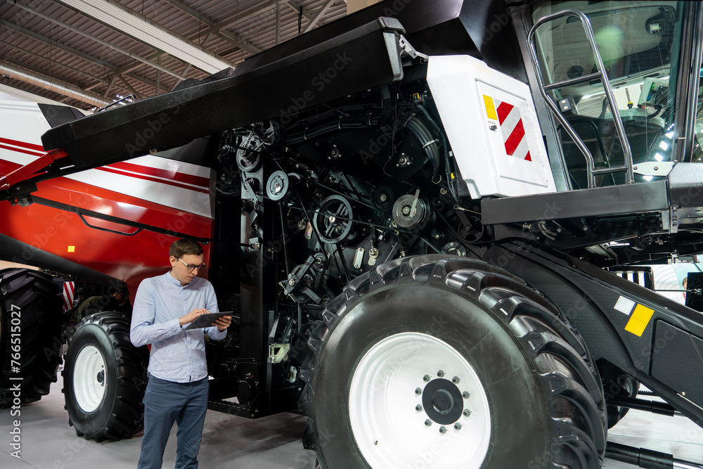 Aufkleber serviceman with digital tablet on a next to ombine harvester with open hood..