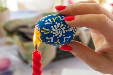On Easter Eve, a woman paints an Easter egg.