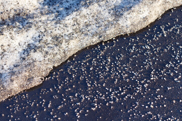 Asphalt is strewn with anti-icing agent in winter, the snow is melting.