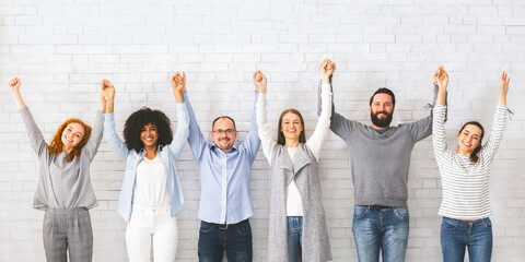 Group of successful friendly people raising connected hands