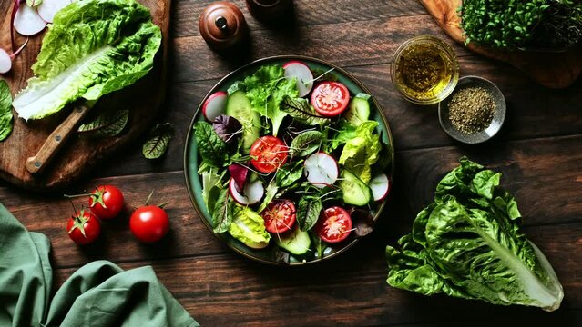 Salad bowl. Fresh vegetables salad cooked of lettuce leaves, cucumber, radish and tomatoes. Stock footage video 4k