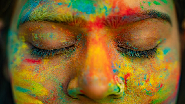Woman celebrating Holi festival with powder colours or gulal, Face closeup portrait