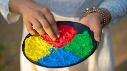 Celebrating Holi festival with powder colours, woman holding gulal plate