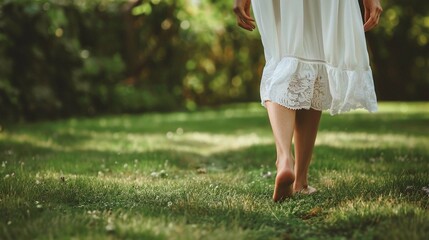 A close up of a barefoot woman in white dress is walking on the grass - Powered by Adobe
