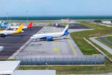 A busy airport tarmac runway with various commercial aircraft planes parked near the terminals.