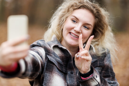 Woman Making a Peace Sign With Cell Phone