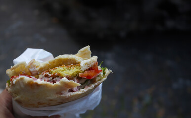 Authentic street food: falafel sandwich with pita bread, hummus, tomatoes, and lettuce - 766546220
