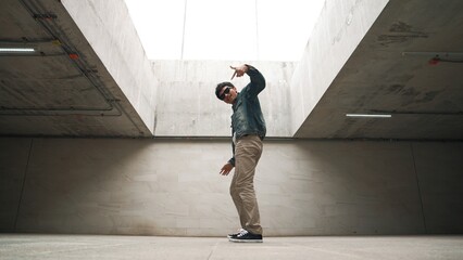 Stylish happy hipster perform break dance or freestyle foot step in building. Professional break...