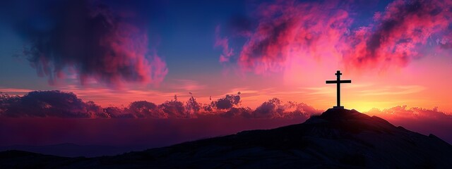 A silhouette of the cross on top of Mount Josef with a colorful sky in the background