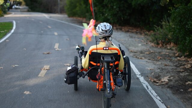 Closeup rear view of elderly senior woman riding a recumbent electric bike on a bike path in Southern California. Filmed in.