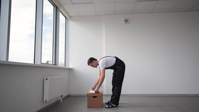 A uniformed loader picked up the parcel in a contactless way. An open office space. A white office with large paneled windows.