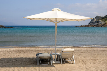 Sunbeds with umbrella on sandy beach of Agios Stefanos. The Greek island of Kos