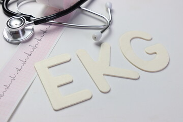 Ekg letters in a white background with a ekg paper and a stethoscope 