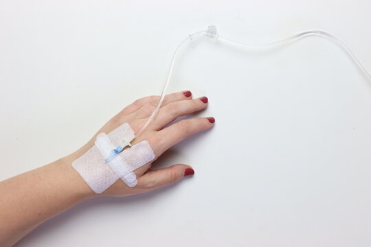 Woman&rsquo;s hand with peripheral catheter in the left side in a white background with copy space in the right