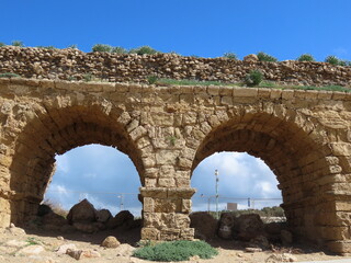 Ancient Roman aqueduct in Caesarea against the blue sky. Traveling around Israel.
