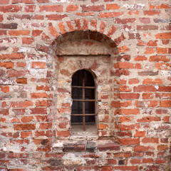 Window with bars in an ancient brick wall.