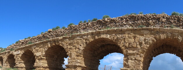 Ancient Roman aqueduct in Caesarea against the blue sky. Traveling around Israel.