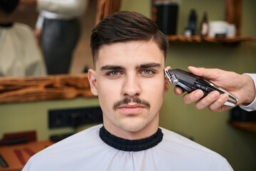 Coiffeur using hair clipper for making stylish hairstyle