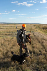 Side view of hunter carrying dead pheasant while walking on field