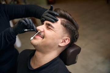 Master barber doing depilation beauty procedure in barbershop