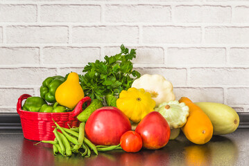 Vegetarian and healthy eating concept; heap of fresh vegetables (tomatoes, green bell peppers, green beans, zucchinis, cabage, cucumbers) on a kitchen's table