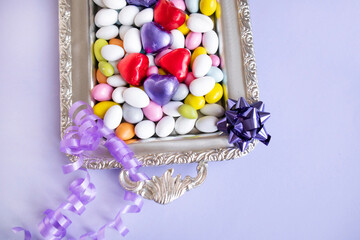 Colorful almond candies were designed on a silver tray with heart-shaped wrapped chocolates.