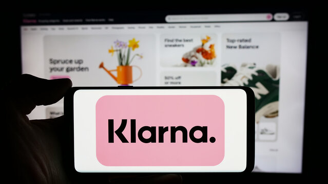 Stuttgart, Germany - 03-16-2024: Person holding cellphone with logo of Swedish fintech company Klarna Bank AB in front of business webpage. Focus on phone display.