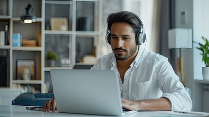 Concentrated man in headphones using laptop in a stylish, modern space.