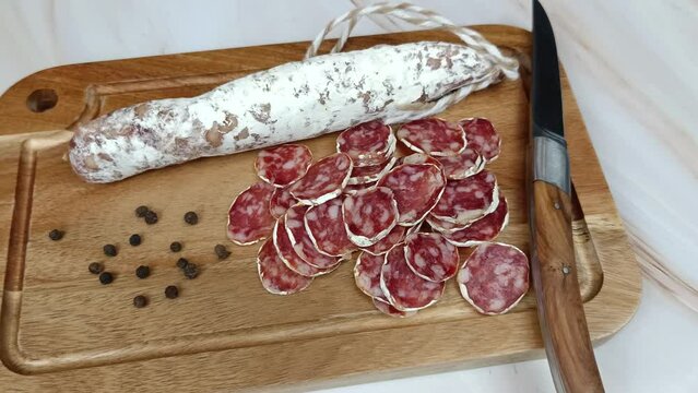 saucisson sec tranch&eacute;, en gros plan, sur une planche &agrave; d&eacute;couper	