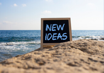 New ideas symbol. Concept word New ideas on black chalk background. Beautiful sea background. Business and New ideas concept. Copy space