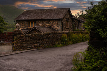 Fototapeta na wymiar Beautiful warm sunset bathes a traditional stone cottage in the Lake District
