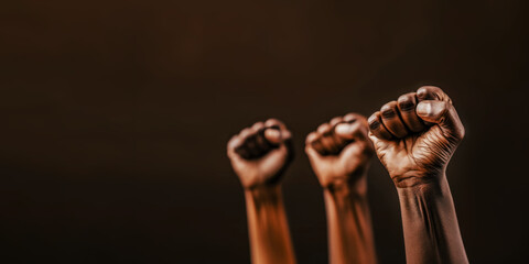 United in Strength: Raised Fists Symbolizing Solidarity and Power. A compelling image of raised fists against a dark background, representing unity and resistance.