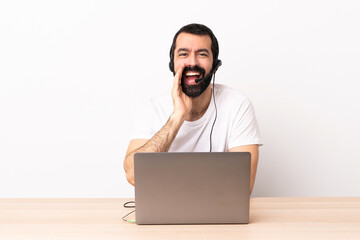 Telemarketer caucasian man working with a headset and with laptop shouting with mouth wide open.