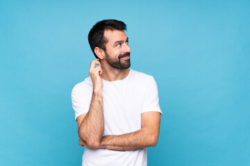 Young man with beard  over isolated blue background thinking an idea