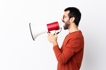 Caucasian handsome man with beard over isolated white background shouting through a megaphone
