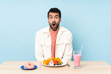 Man at a table having breakfast waffles and a milkshake with surprise facial expression