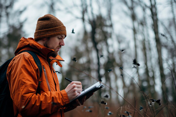 Naturalist biologist taking notes in field notebook. - obrazy, fototapety, plakaty