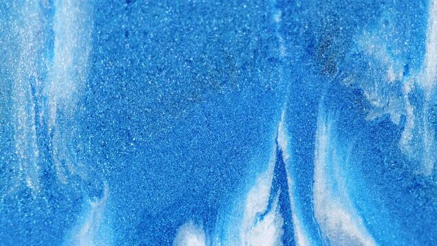 Sparkling ink drip. Glitter fluid. Defocused blue white color shiny texture paint gloss wave motion winter abstract art background.