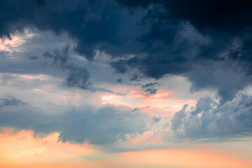 Dramatic pre-storm sky with orange-pink hues blending into dark blue clouds. Atmospheric scene before storm