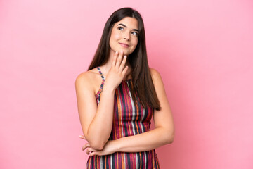 Young Brazilian woman isolated on pink background looking up while smiling