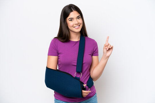 Young Brazilian woman with broken arm and wearing a sling isolated on white background showing and lifting a finger in sign of the best
