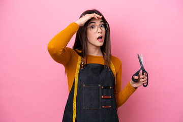 Young Brazilian seamstress woman isolated on pink background doing surprise gesture while looking...