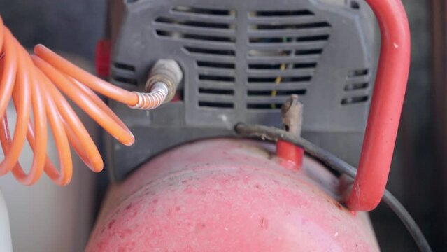 Dusted air compressor with spiral cable in workshop, machine with air pressure used in industrial purposes