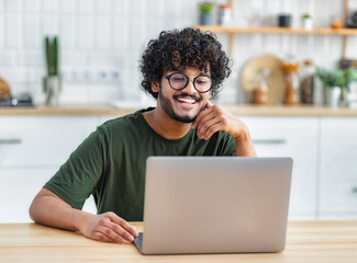 Portrait of successful freelancer or student working on new project. Smiling young indian man using...