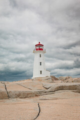 Fototapeta na wymiar Lighthouse on the rocks on a cloudy sky