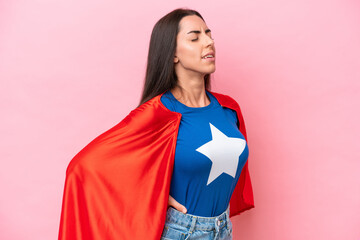 Super Hero Caucasian woman isolated on pink background suffering from backache for having made an effort