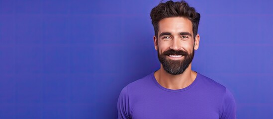 The photo features a smiling man wearing a purple shirt and sporting a beard.