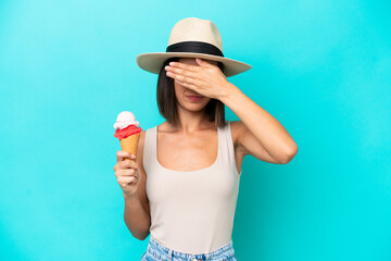 Young caucasian woman holding an ice cream isolated on blue background covering eyes by hands. Do...