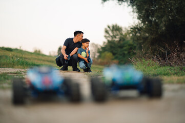 A father kissing his son in the back of the head while racing with toy cars.